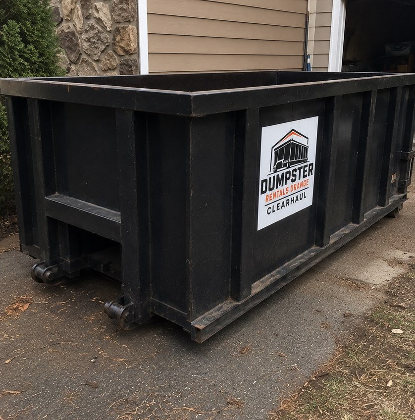 Black roll-off dumpster placed on a residential driveway